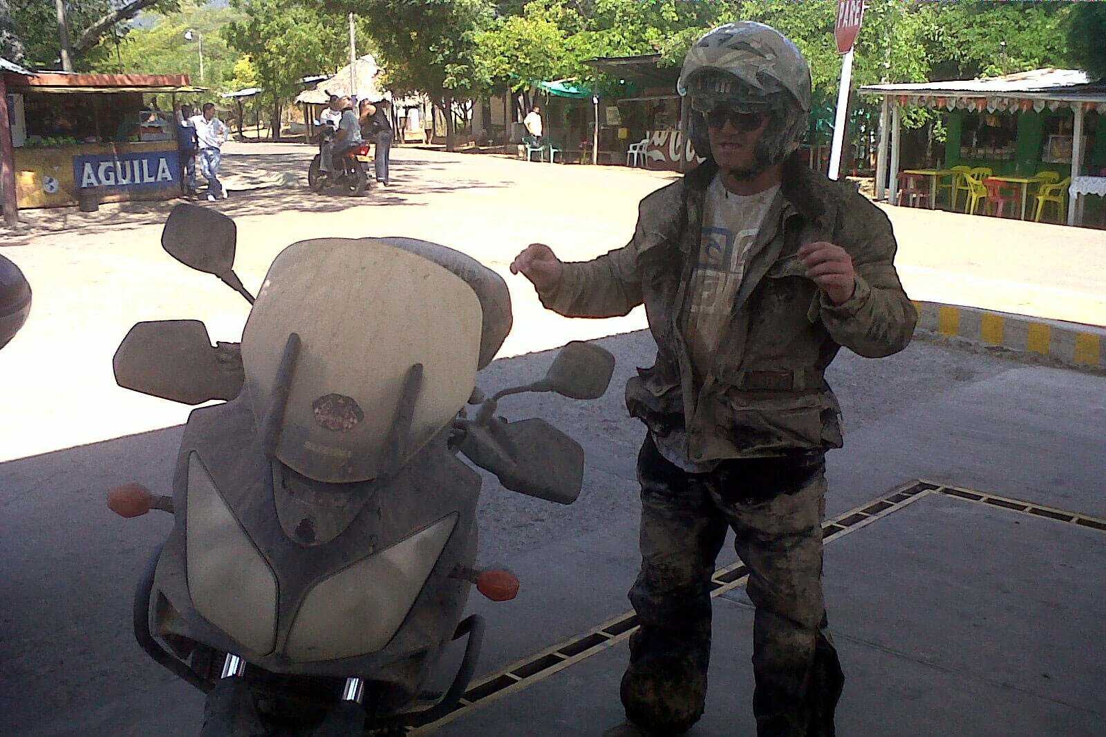 Man in motorcycle gear covered in dirt.